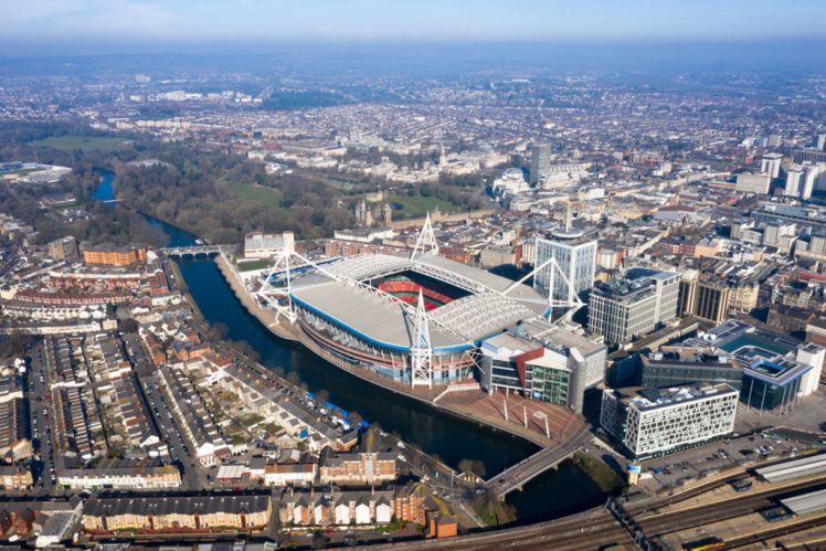 Cardiff aerial view Wales capital cityscape panoramic skyline feat. River Taff and city center in UK with Principality Stadium home of Welsh rugby union, plus football around town center from above.